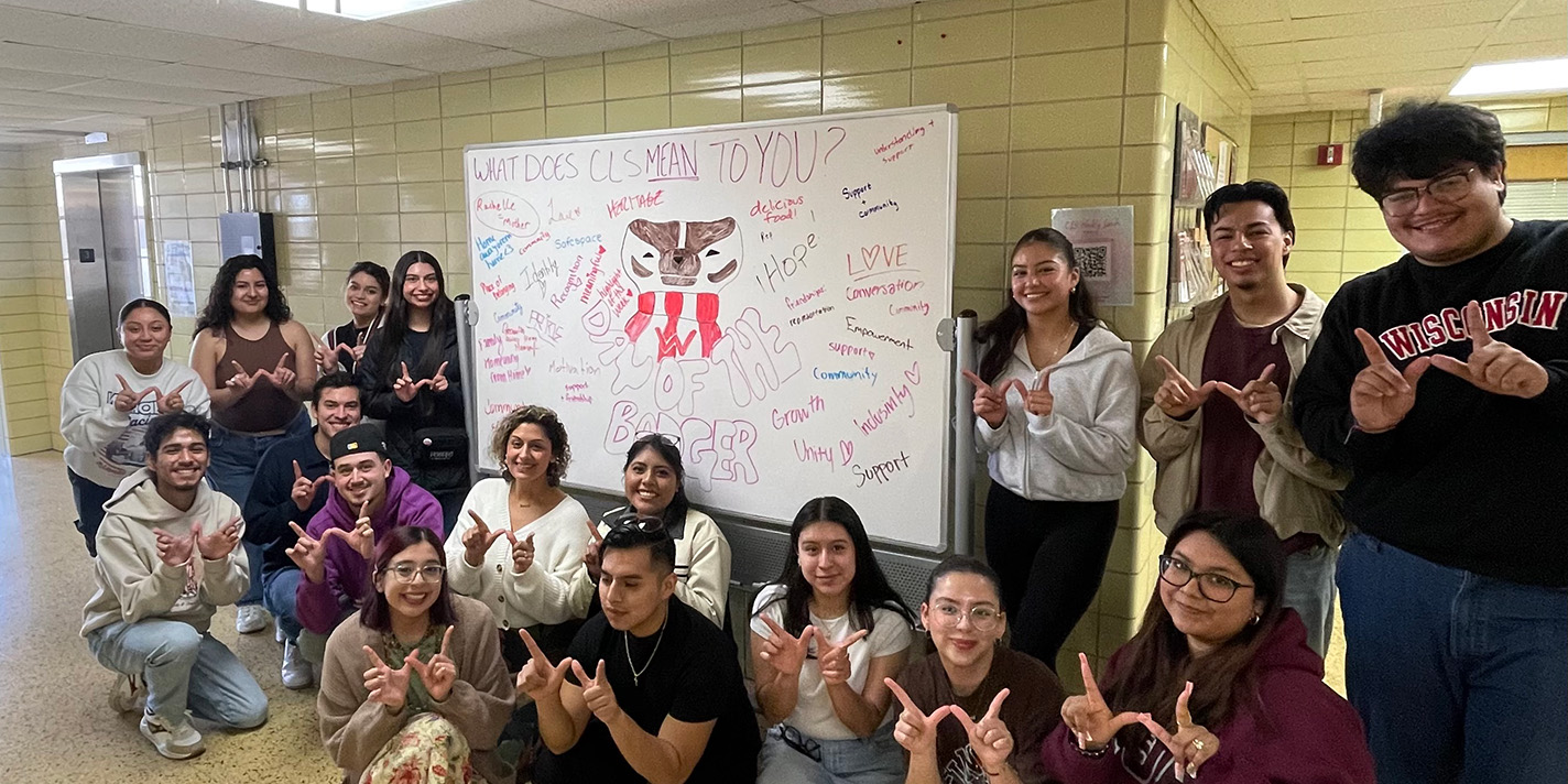 Students and faculty shown with their hands forming a W